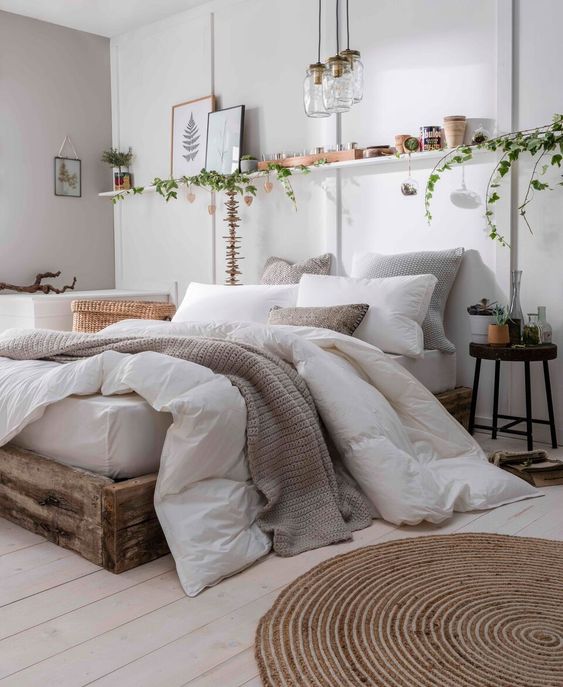Linens thrown on a bed with photo frames, plants and lights as room decor